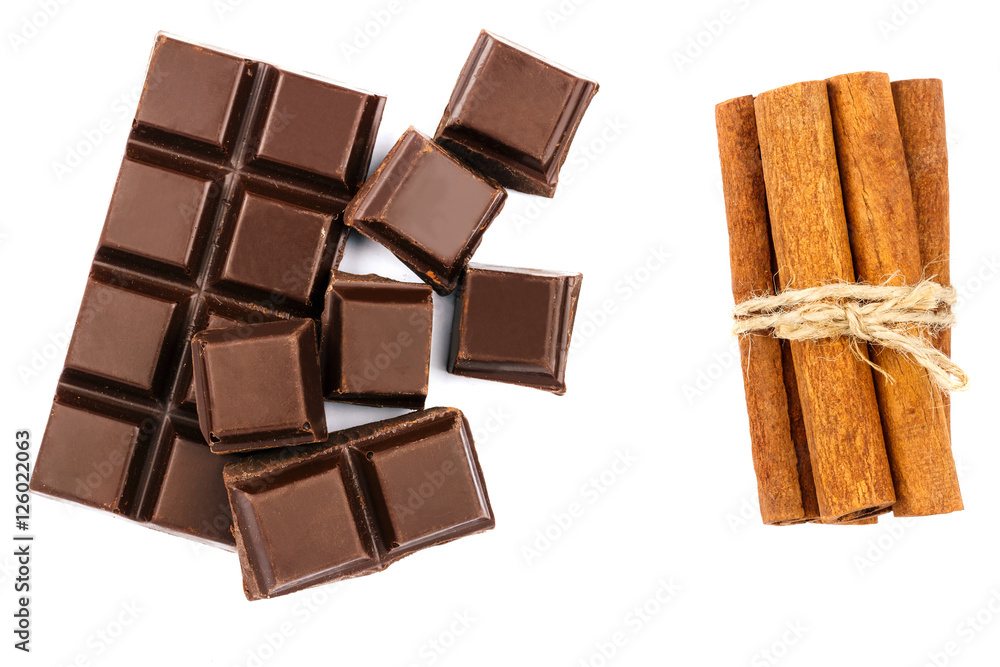Dark chocolate bar, cubes and cinnamon sticks isolated on white background, top view. Dark chocolate bar, cubes and cinnamon sticks isolated on white background, top view.