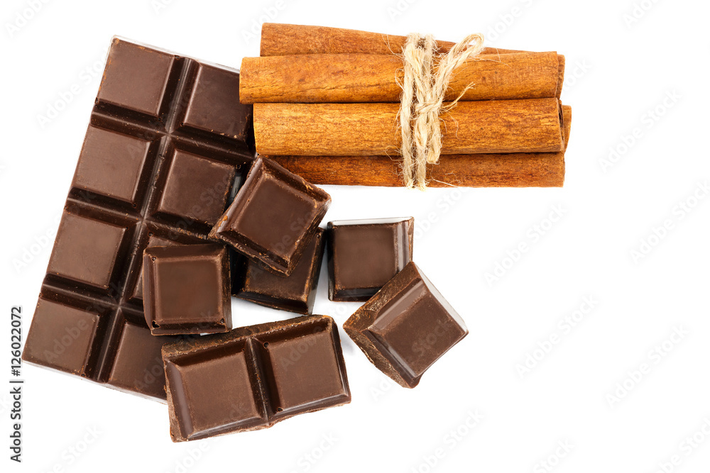 Fototapeta premium Dark chocolate bar, cubes and cinnamon sticks isolated on white background, top view.