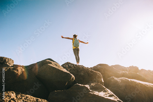 Silhouette of a young woman practicing yoga on a rocky shore