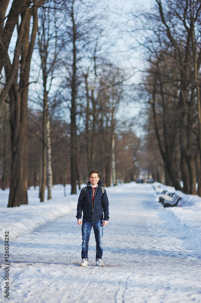 Young handsome smiling man stands in a city Park on a clear winter day