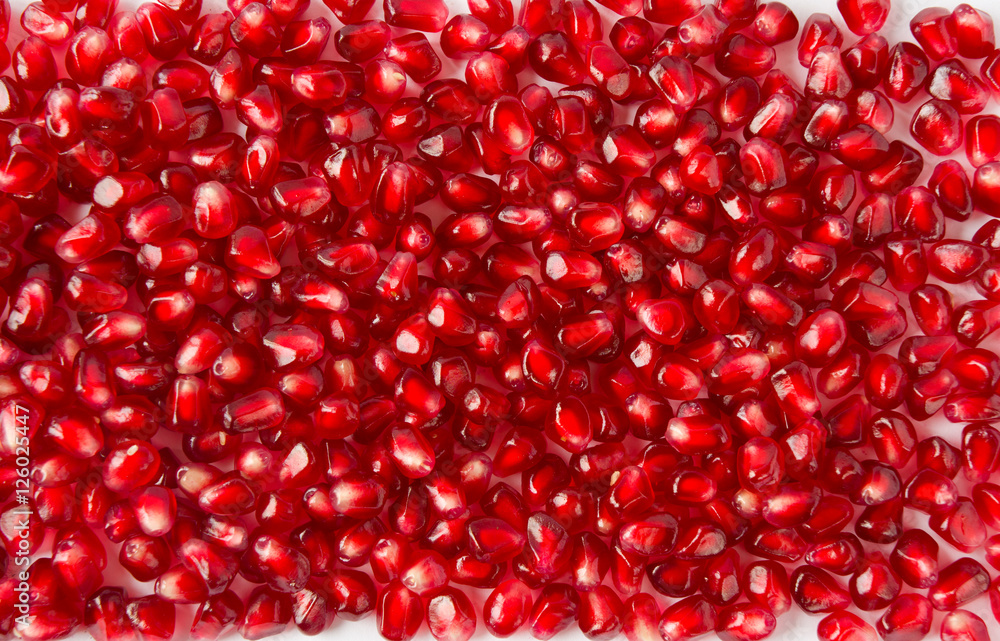 Background made of red pomegranate seeds. The scattered red grains of a pomegranate. Background made of red pomegranate seeds. The scattered red grains of a pomegranate.