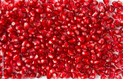 Background made of red pomegranate seeds. The scattered red grains of a pomegranate.
