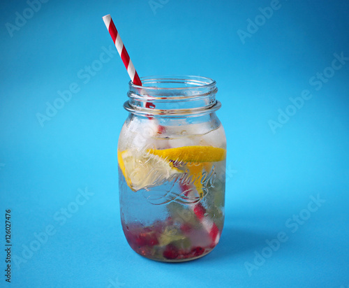 Освежающий натуральный домашний лимонад с лимоном, мятой и красной смородиной в банке на синем фоне 