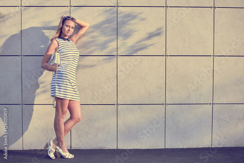 Portrait of sport happy girl with neutral background. City walking concept. Young beautiful woman portrait in dress and sunglasses. Copy space for advertising text.