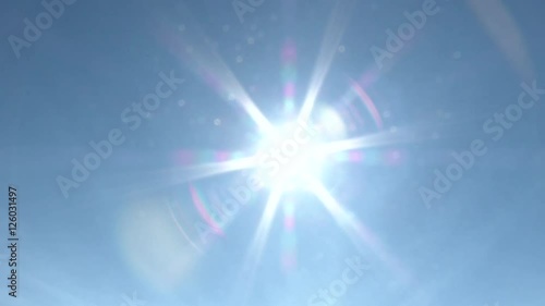 Clear blue sky day with bright sun shining and flare as camera pans then zoom transition to white.