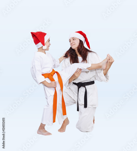 With black and orange belt in caps of Santa Claus sport family are training kick leg