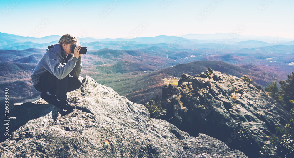 Man with a camera on top of a cliff