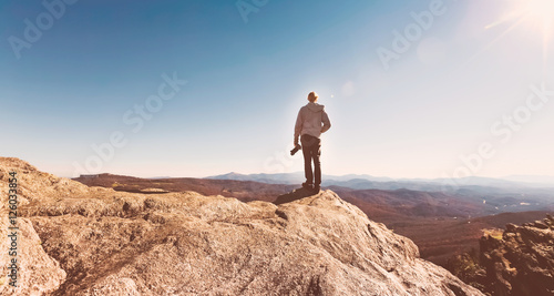 Man with a camera on top of a cliff