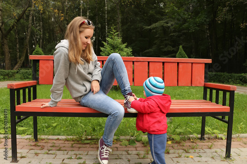 A small child helps to tie the shoes of his mother in the Park