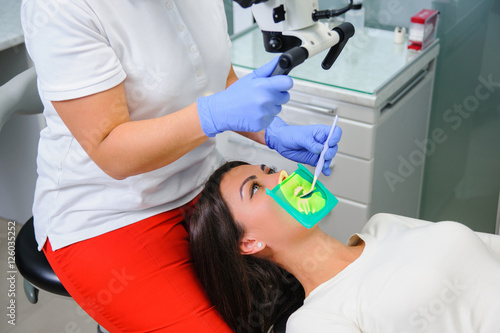 Female dentist getting ready for teeth treatment with microscope