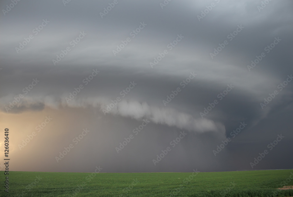 A monstrous supercell thunderstorm appears through the haze.