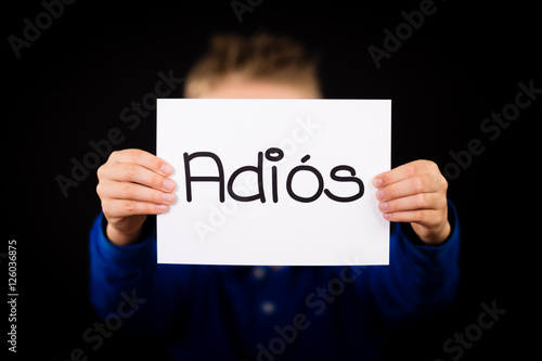 Child holding sign with Spanish word Adios - Goodbye