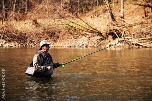 Middle-aged fisherman catching grayling in the river