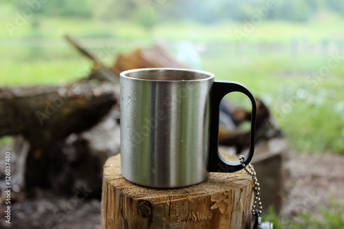 Metal mug on a stump on a background of fire. Cup on a log