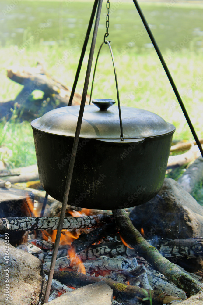 Cooking outdoors. Cauldron on a fire in the forest Cooking outdoors. Cauldron on a fire in the forest