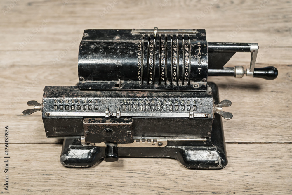 Old rusty retro calculator black standing on a wooden table Old rusty retro calculator black standing on a wooden table