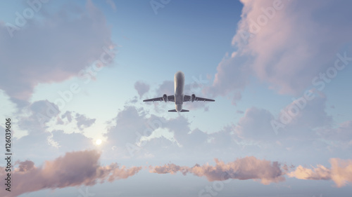 Billede på lærred Passenger airplane flying overhead high in the sky above cumulus clouds at sunset or sunrise
