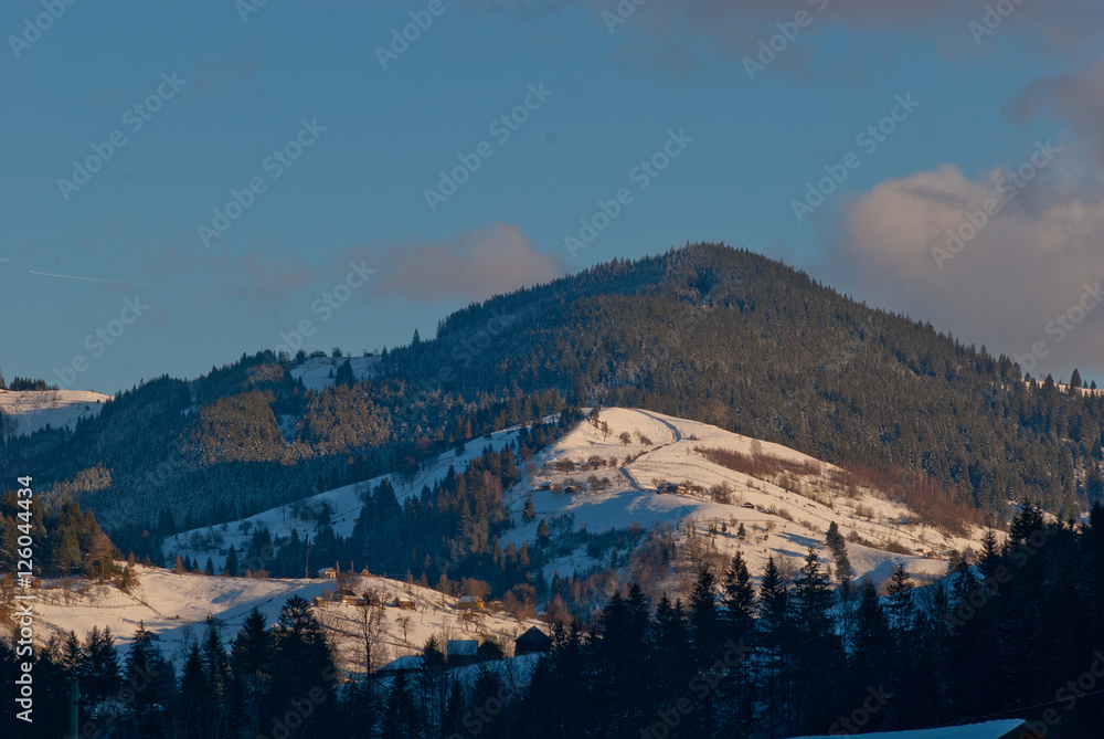 Top of mountains covered with snow lit by winter sun