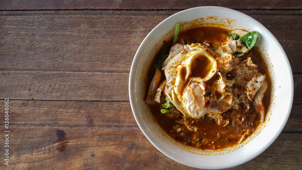 Hot and spicy noodle egg with soup on the wooden table 