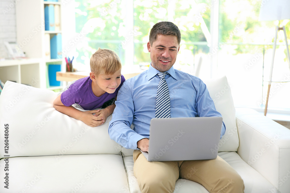 Little boy watching his father working with laptop Little boy watching his father working with laptop