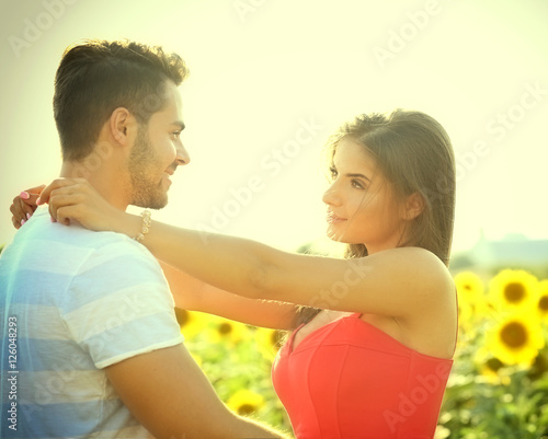 Young couple hugging and looking at each other in a field of sunflowers