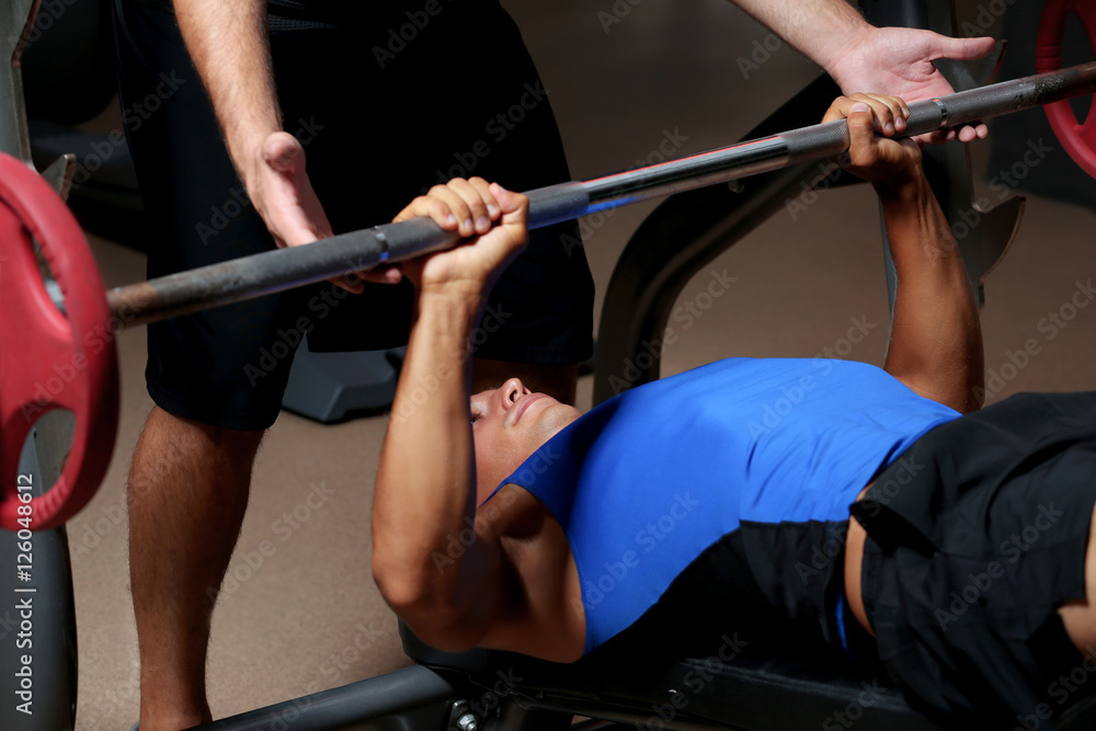 Personal coach helping man with barbell in gym Personal coach helping man with barbell in gym