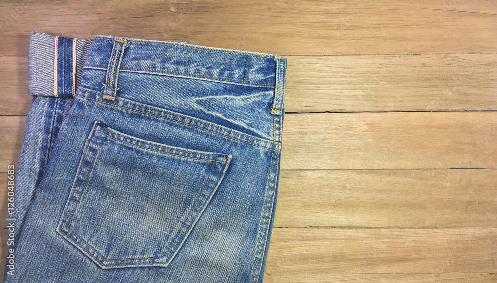 Light blue jeans, seam, and pocket on a brown wooden background, copy space Light blue jeans, seam, and pocket on a brown wooden background, copy space