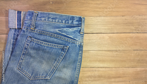 Light blue jeans, seam, and pocket on a brown wooden background, copy space