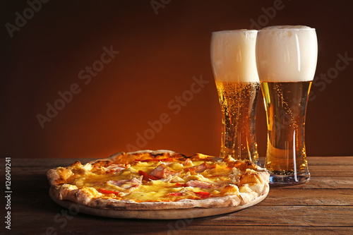 Tasty pizza with beer on wooden table