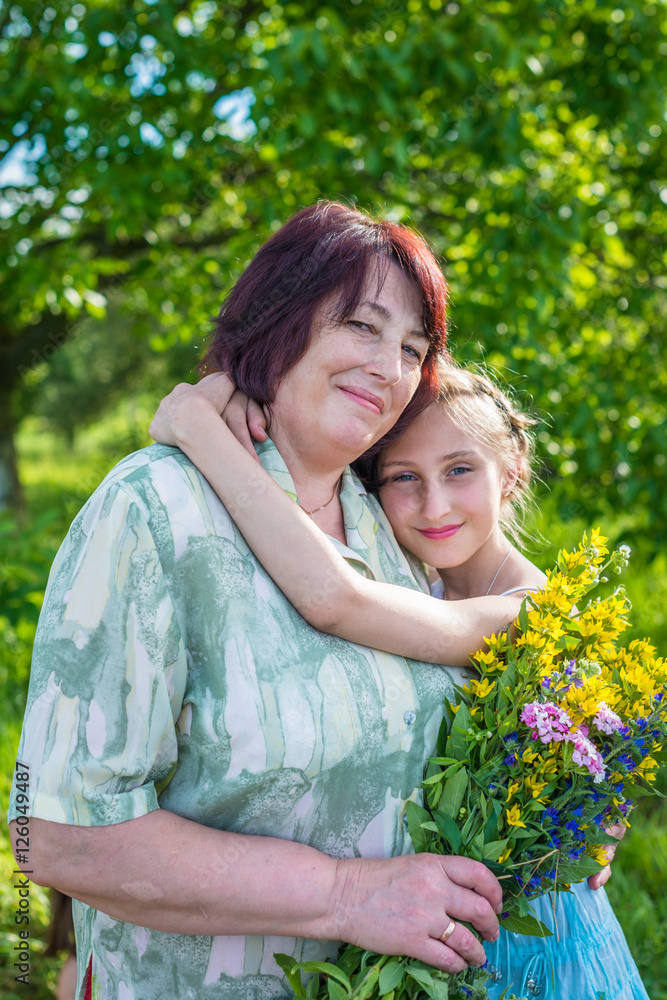 granddaughter hugs her grandmother in the garden granddaughter hugs her grandmother in the garden