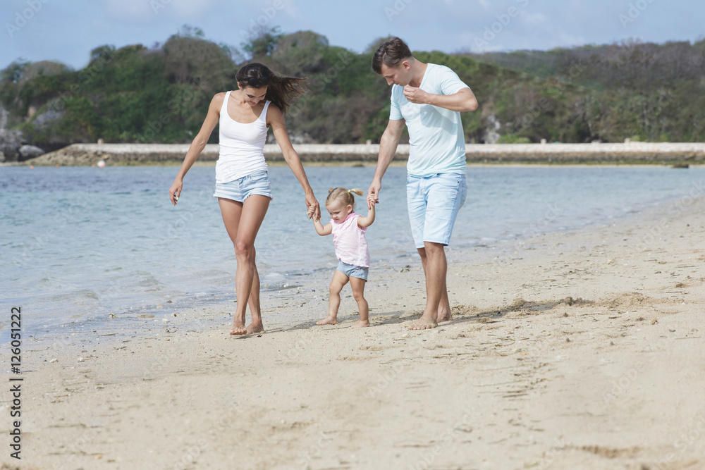 young parents and their cute little daughter are holding hands w