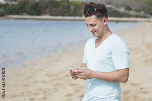 young man texting on mobilephone at the beach