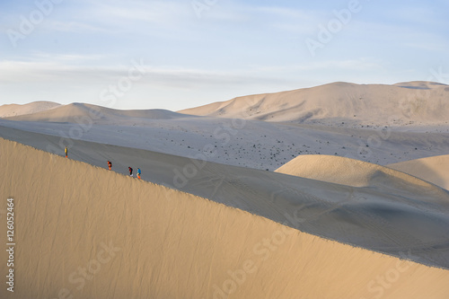 Tourists climb sand dunes in Dunhuang
