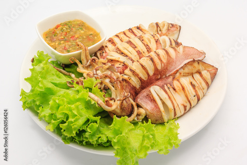 grilled squid serve with Thai hot and spicy seafood and fresh Lettuce in white plate on a white background, Top view with copy space and text