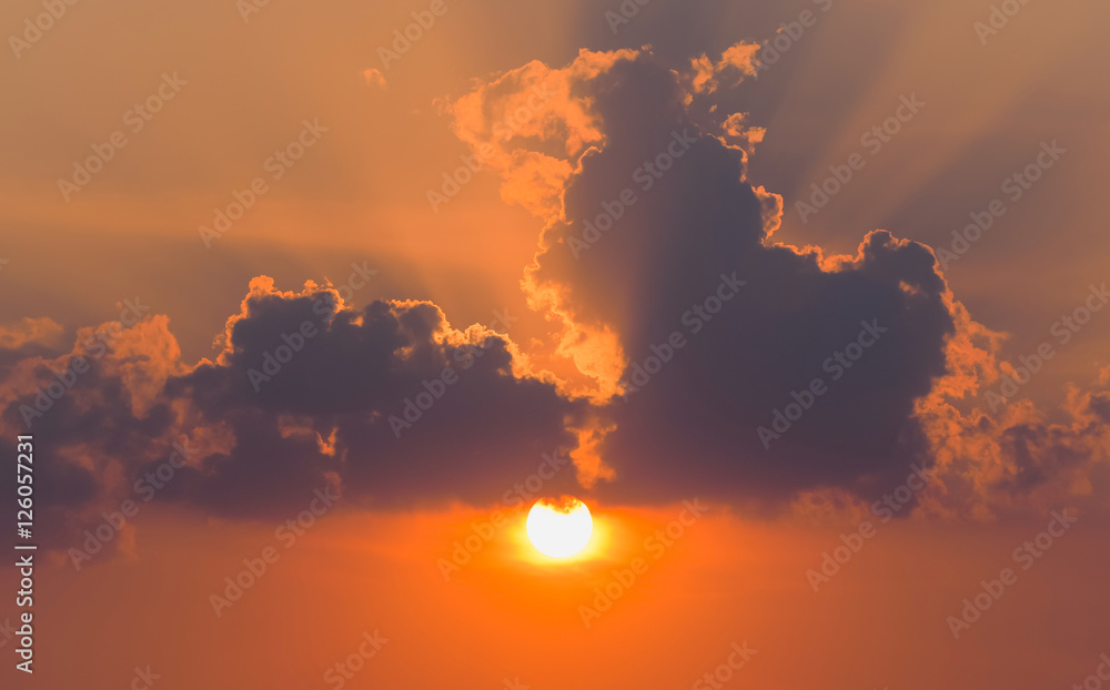 Summer sunset. The setting sun in a cloudy sky background