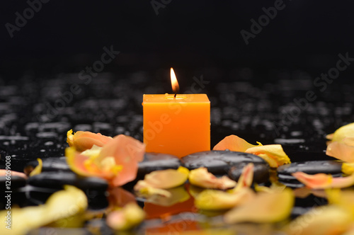 Yellow rose petals with two white candle and therapy stones  