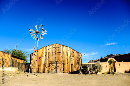 Foto old wooden barn with rusty dilapidated windmill and rundown buggy against blue s