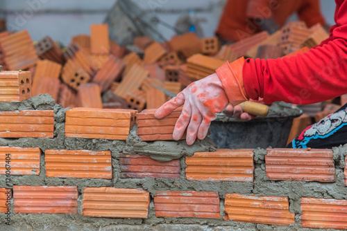 Obraz na płótnie Worker installing red brick for construction site