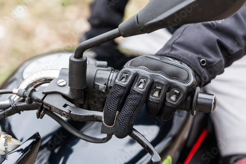 Biker on motorcycle, close-up view on hands on handlebars.