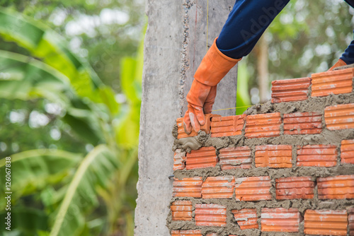 Obraz na płótnie Worker installing red brick for construction site