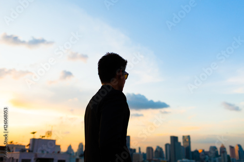 Young man walking in the city against a beautiful sunset. 
