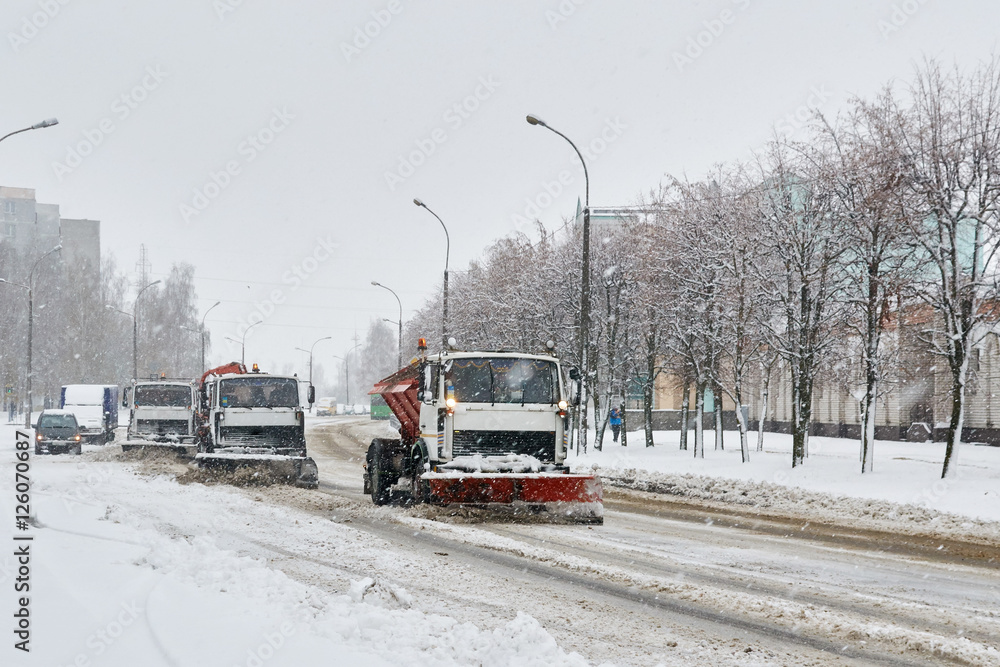 column of special vehicles , shoveling snow in the street in the snow