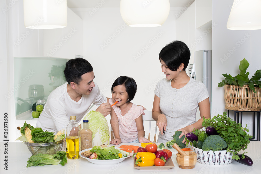 Happy Asian family preparing food in the kitchen.