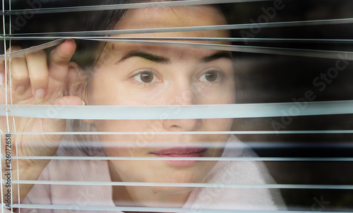 Girl looking through the blinds photo