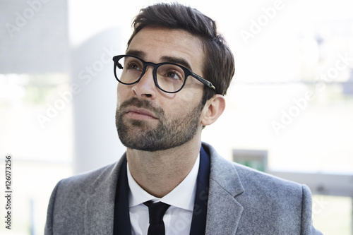 Thoughtful businessman in glasses, looking up