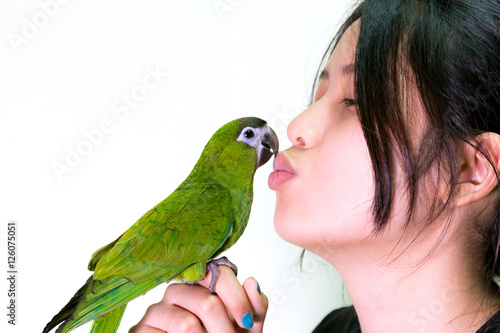 Green macaw bird pet kiss to woman.