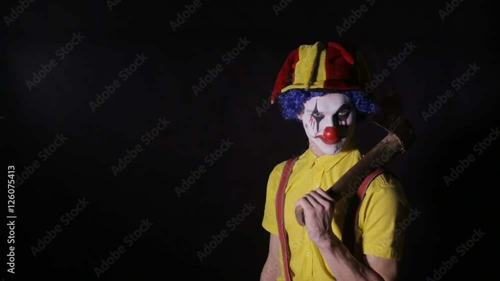 Scary clown with an axe in a dark room. Frightening jester, clown, buffoon. HD. Scary clown with an axe in a dark room. Frightening jester, clown, buffoon. HD.