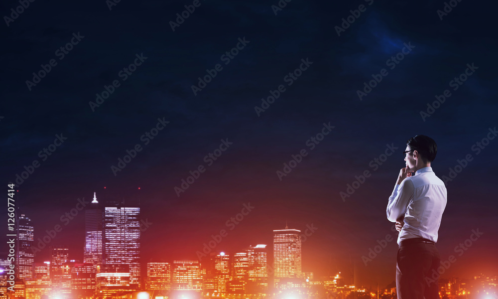 Businessman viewing night glowing city Businessman viewing night glowing city