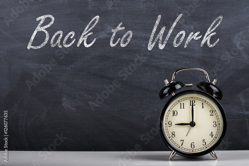 Retro alarm clock and text "Back to Work" written with chalk on the blackboard.