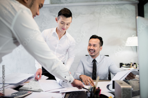 Young Asian coworkers discussing work in the office. photo